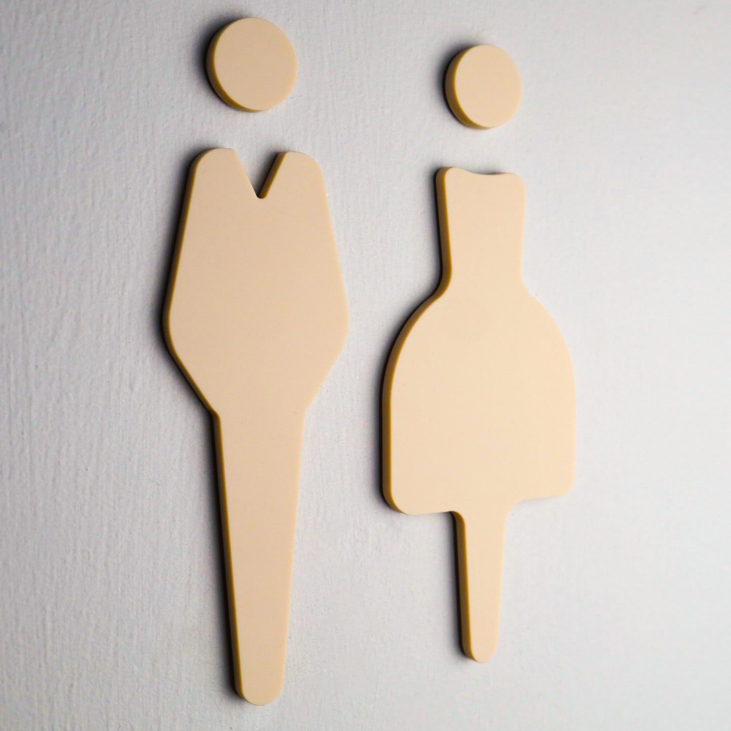 Close-up of elegant beige restroom sign featuring clear ladies and gents symbols