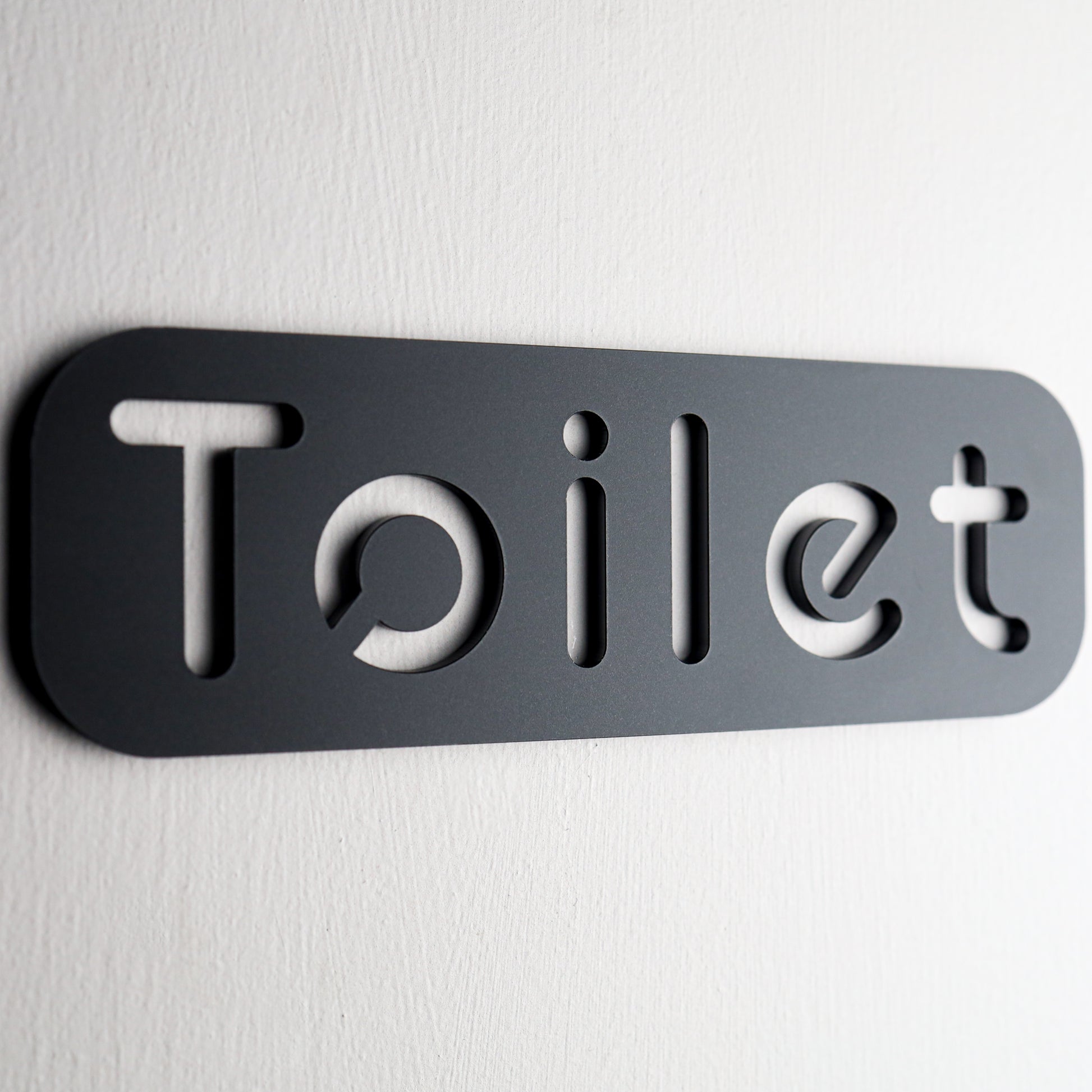 Black acrylic toilet sign with stone texture on a white background