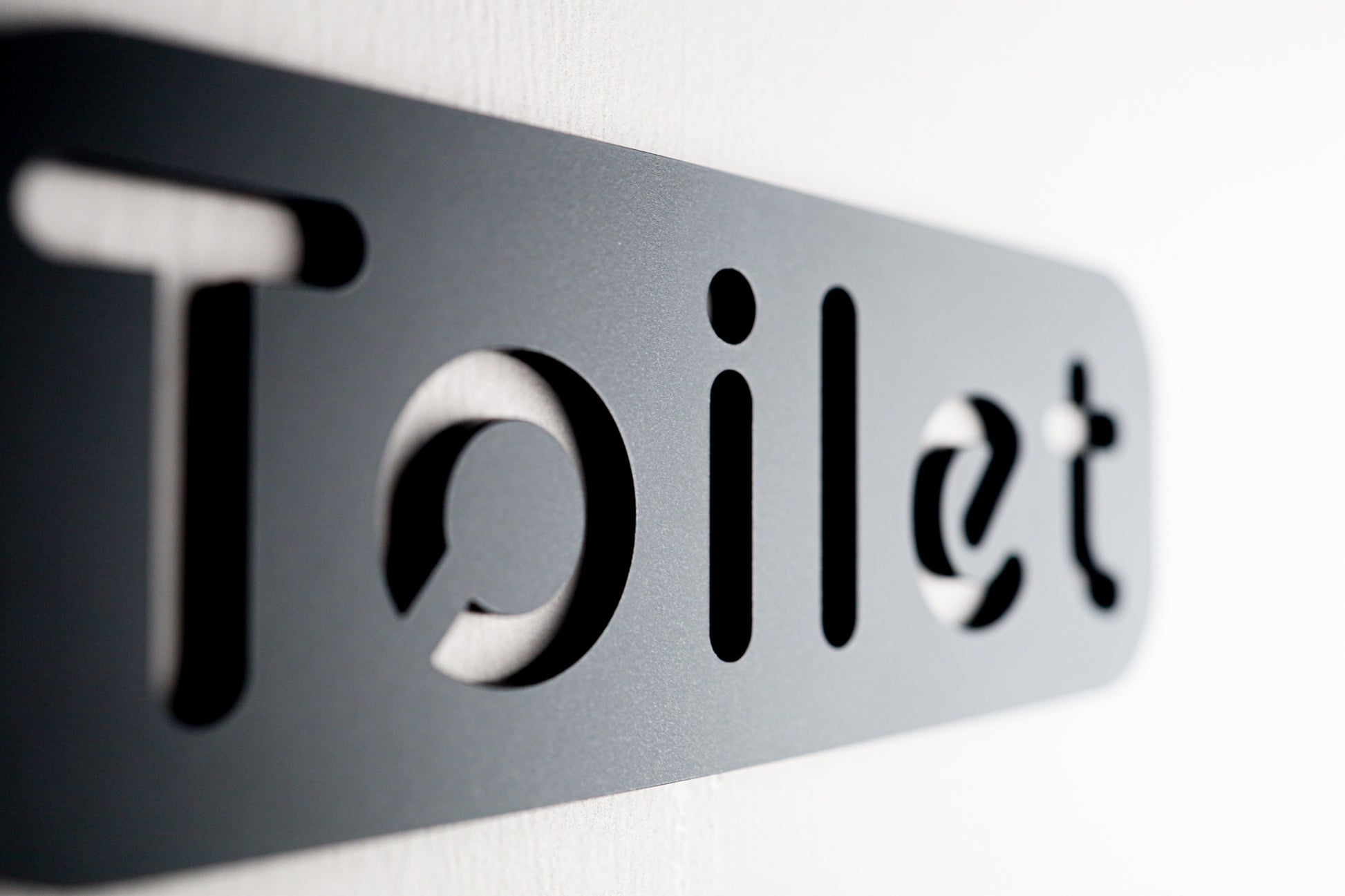 Close-up of sleek black restroom sign with cut-out lettering