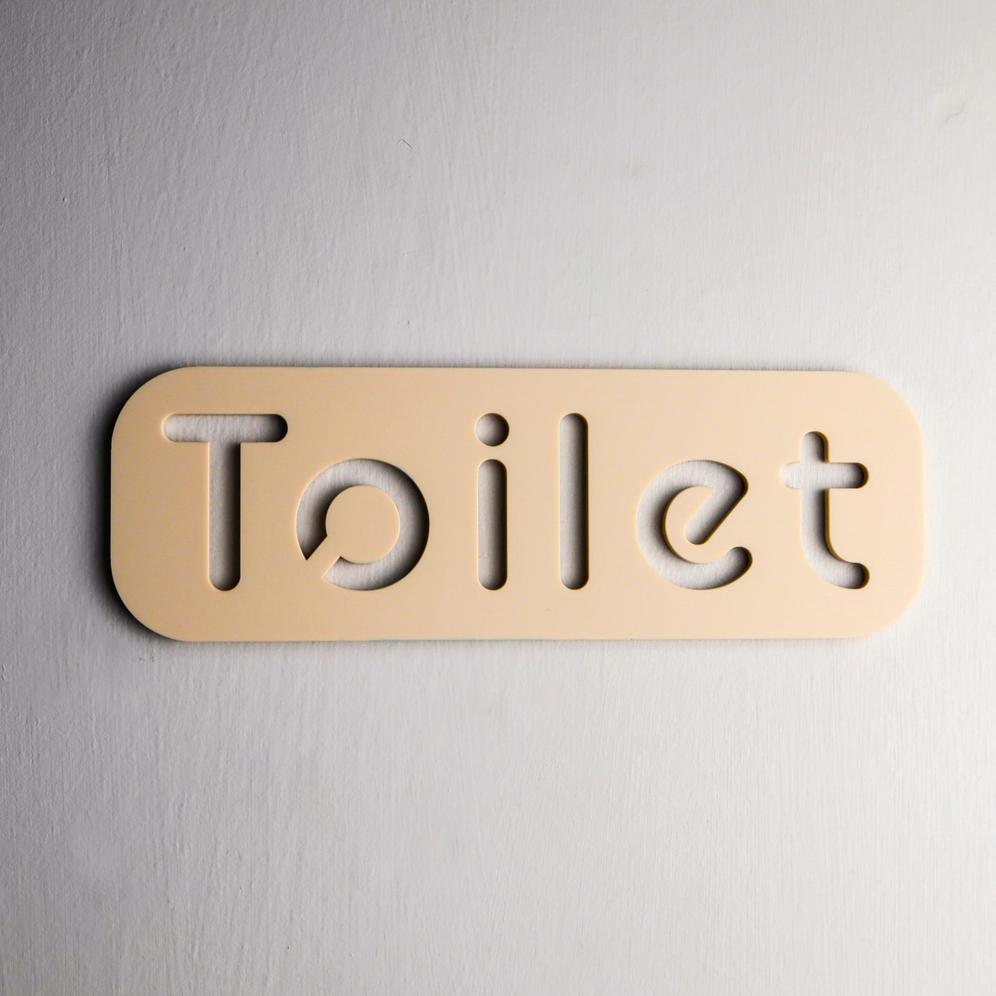 Modern self-adhesive toilet sign with minimalist design on a bathroom door.