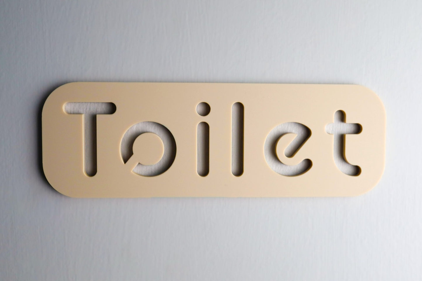 High-quality beige restroom sign with stone texture mounted on a door.