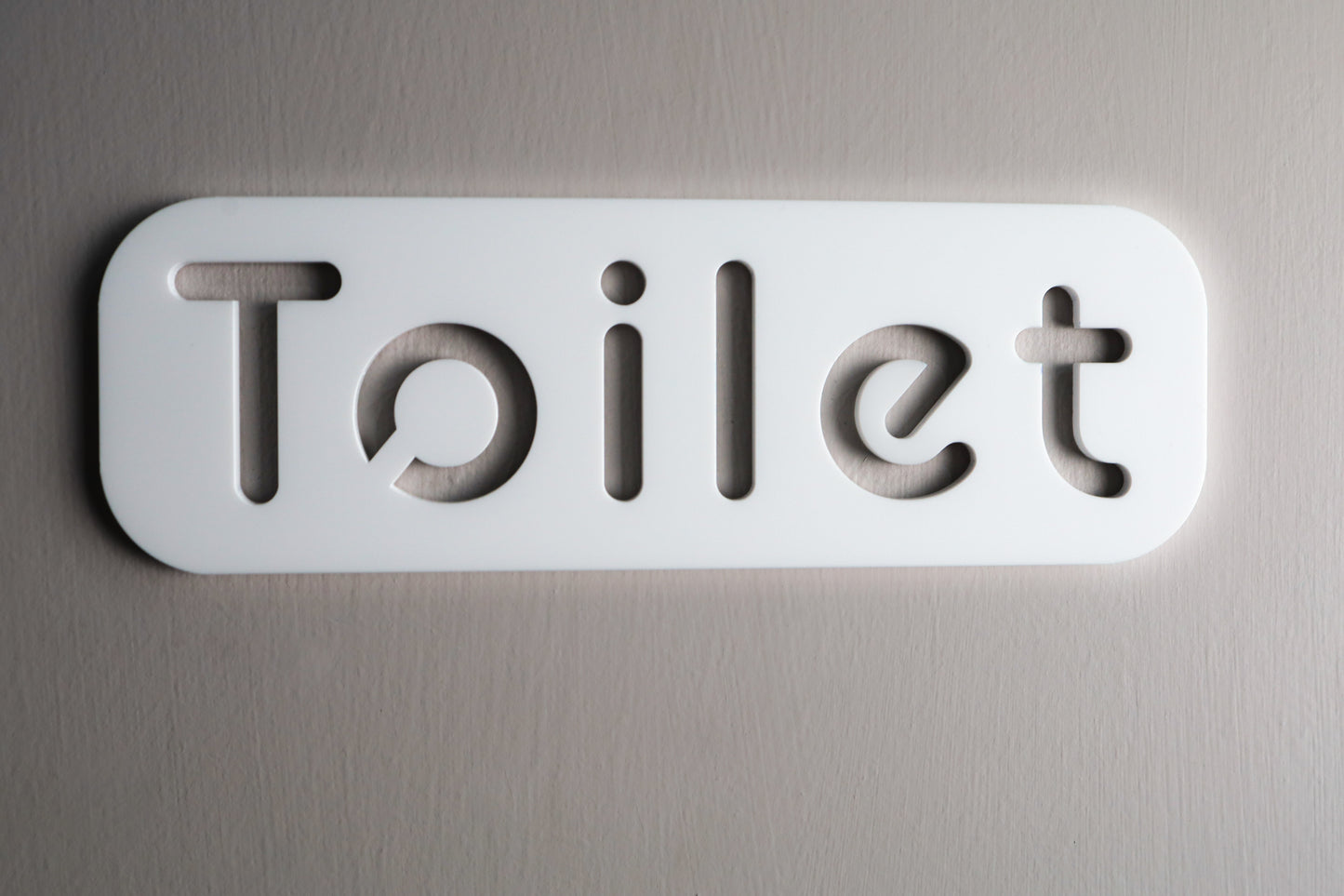 Modern white acrylic toilet sign with minimalist design and stone texture.