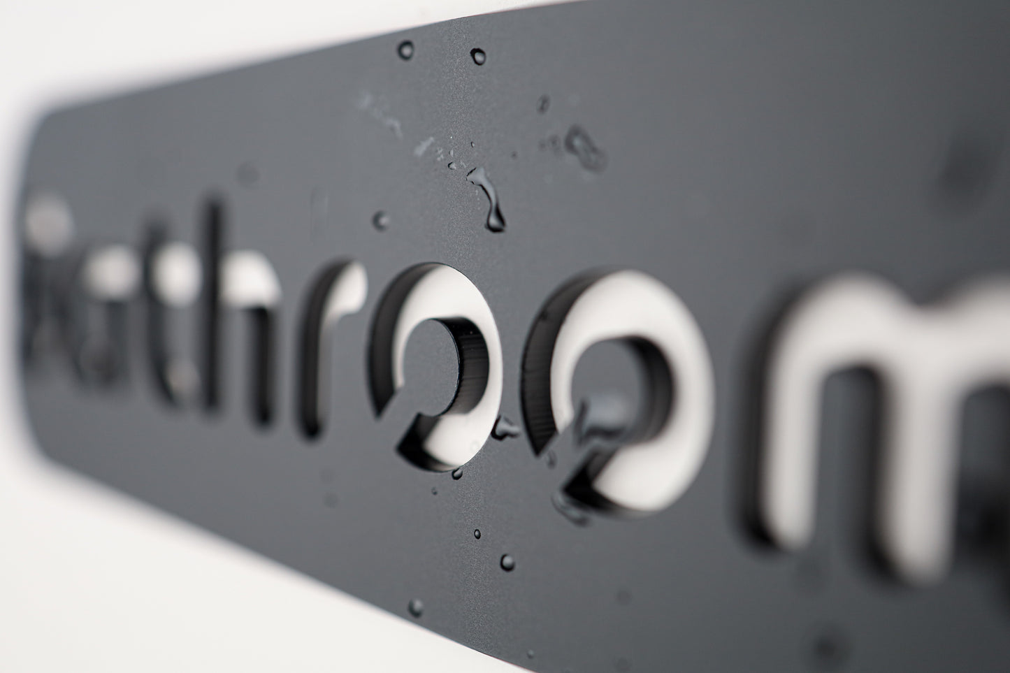 Elegant "Bathroom" sign crafted from premium black acrylic with a stone texture finish.