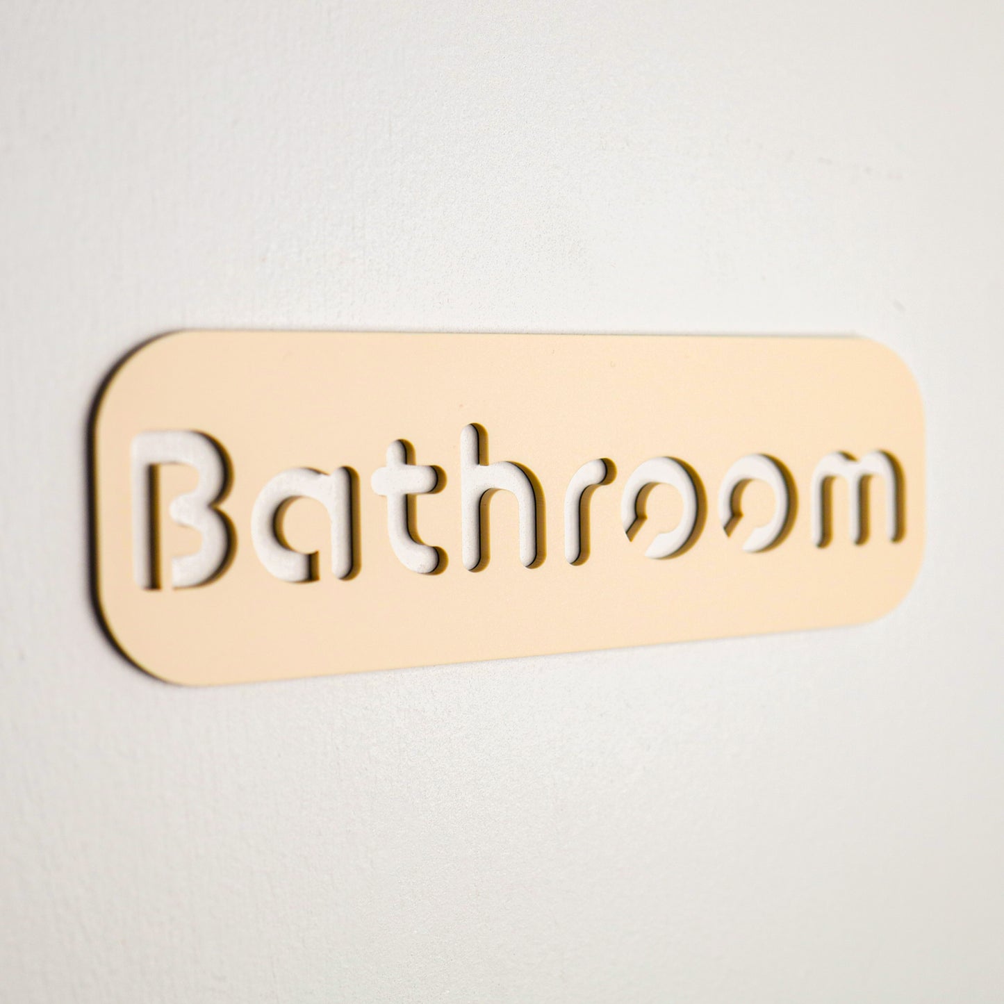 Sleek beige restroom sign with elegant cut-out lettering, ideal for high-moisture environments