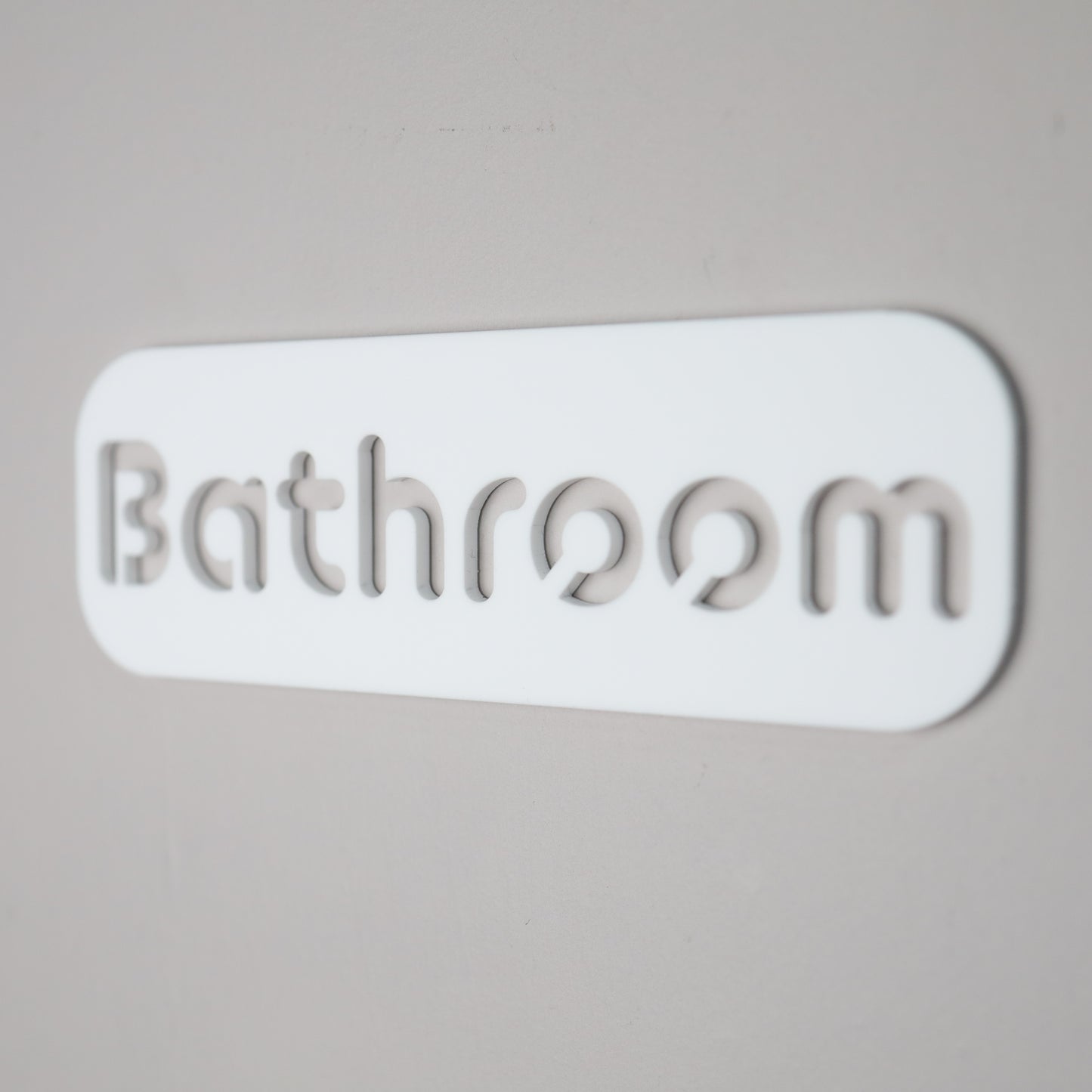 Contemporary "Bathroom" sign mounted on a smooth wall with self-adhesive backing