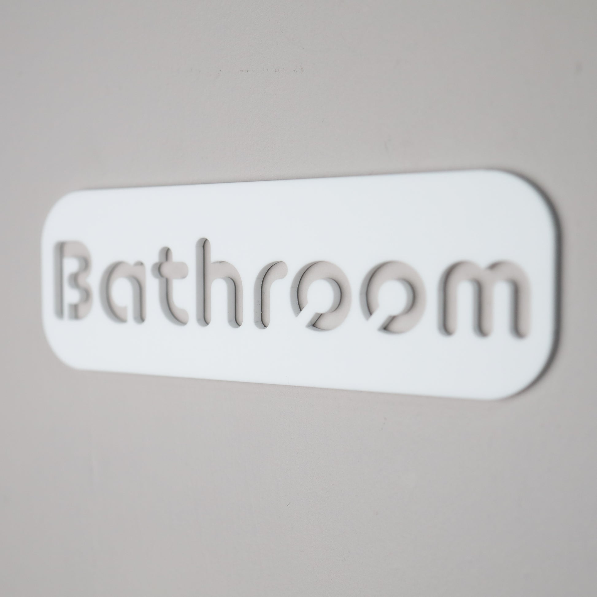 Contemporary "Bathroom" sign mounted on a smooth wall with self-adhesive backing