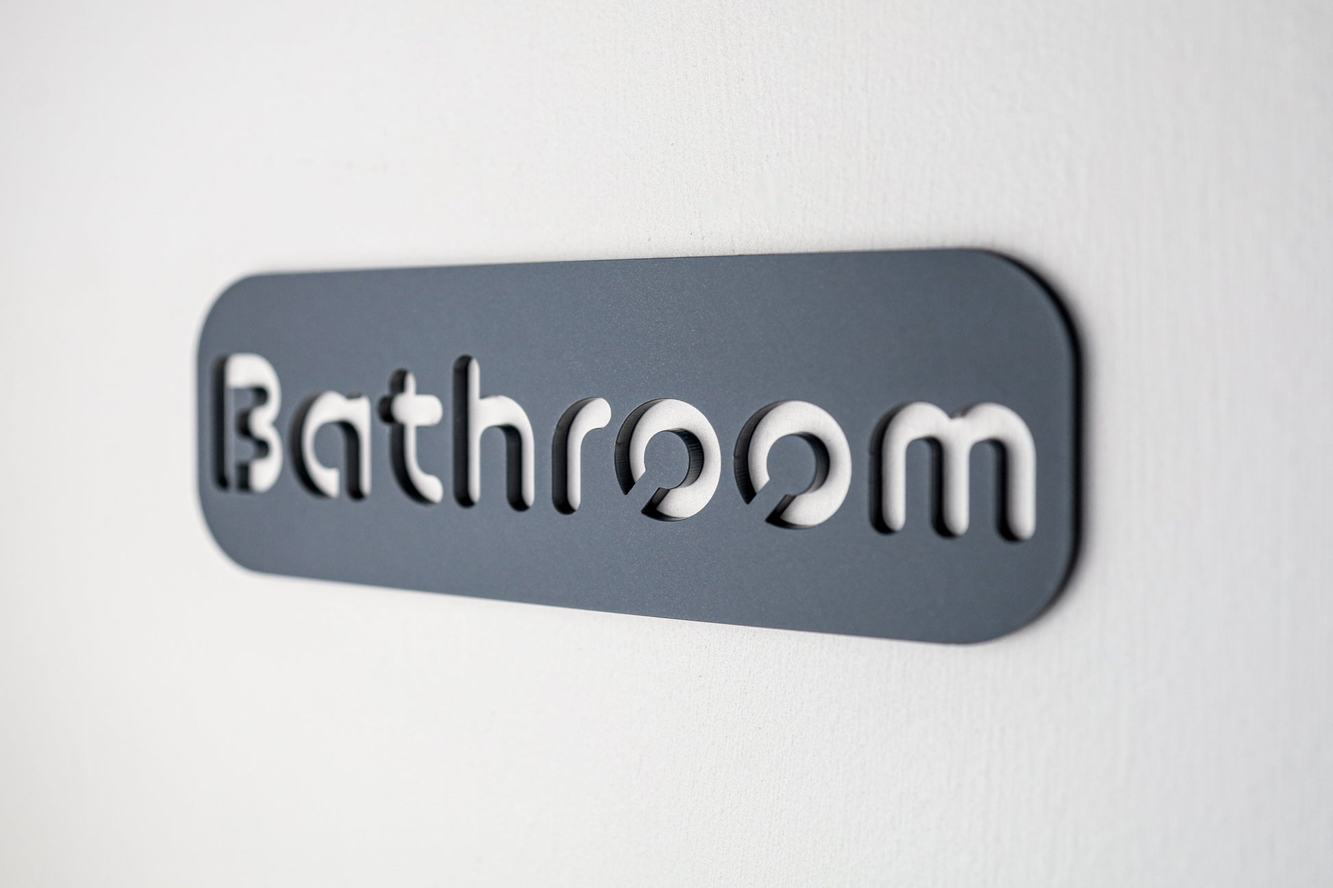 Premium bathroom wall sign featuring black cut-out letters on textured grey acrylic