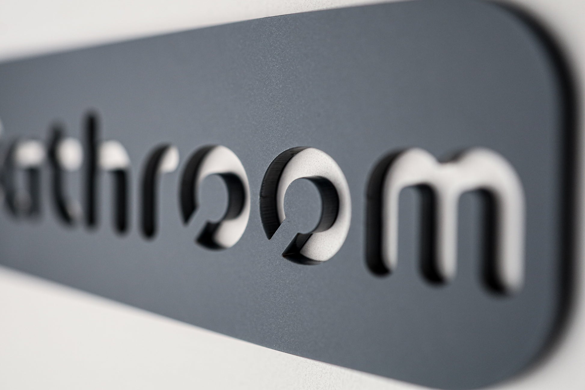 Sleek and modern 'Bathroom' sign in black acrylic on grey stone texture backdrop