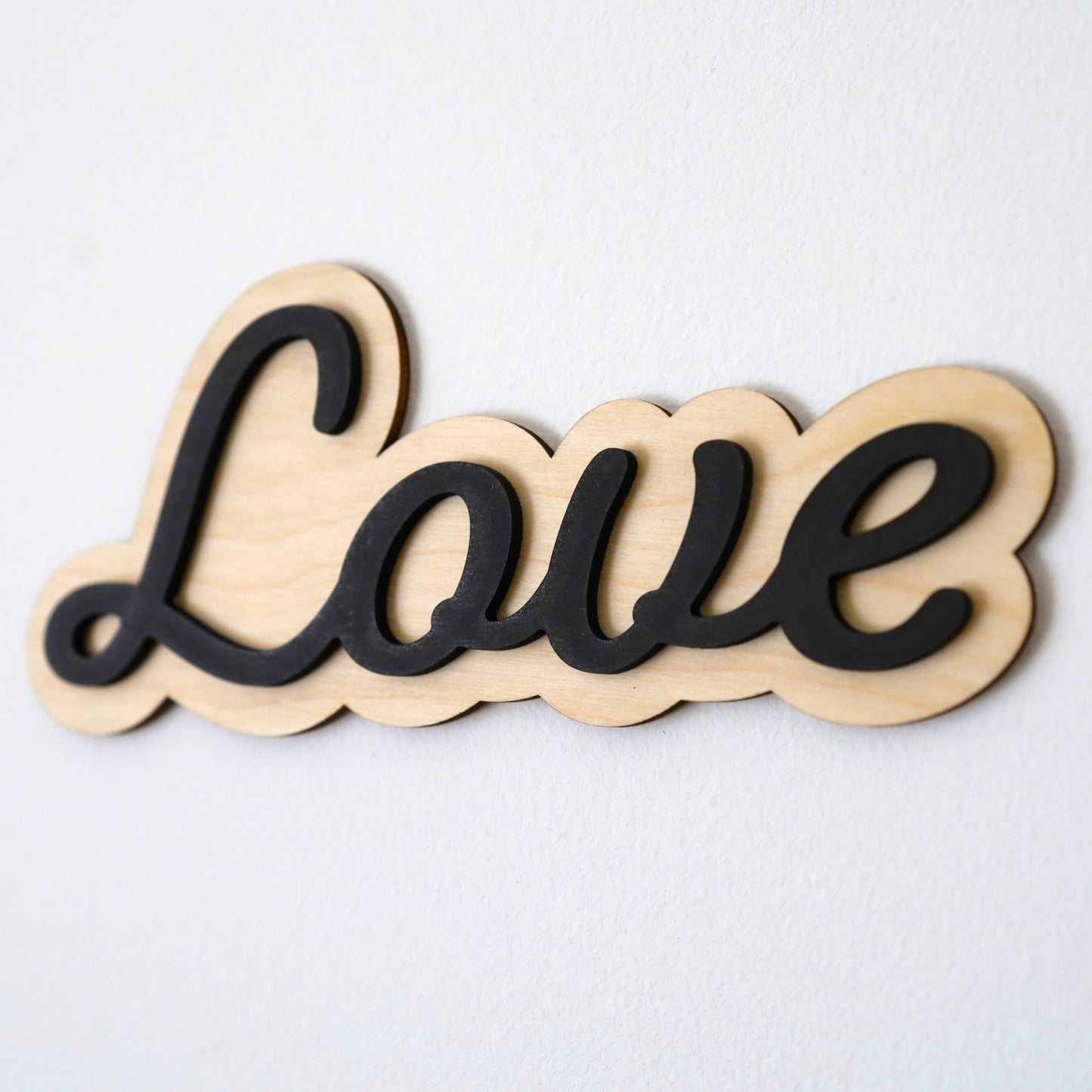 Elegant cursive 'Love' sign on natural birchwood