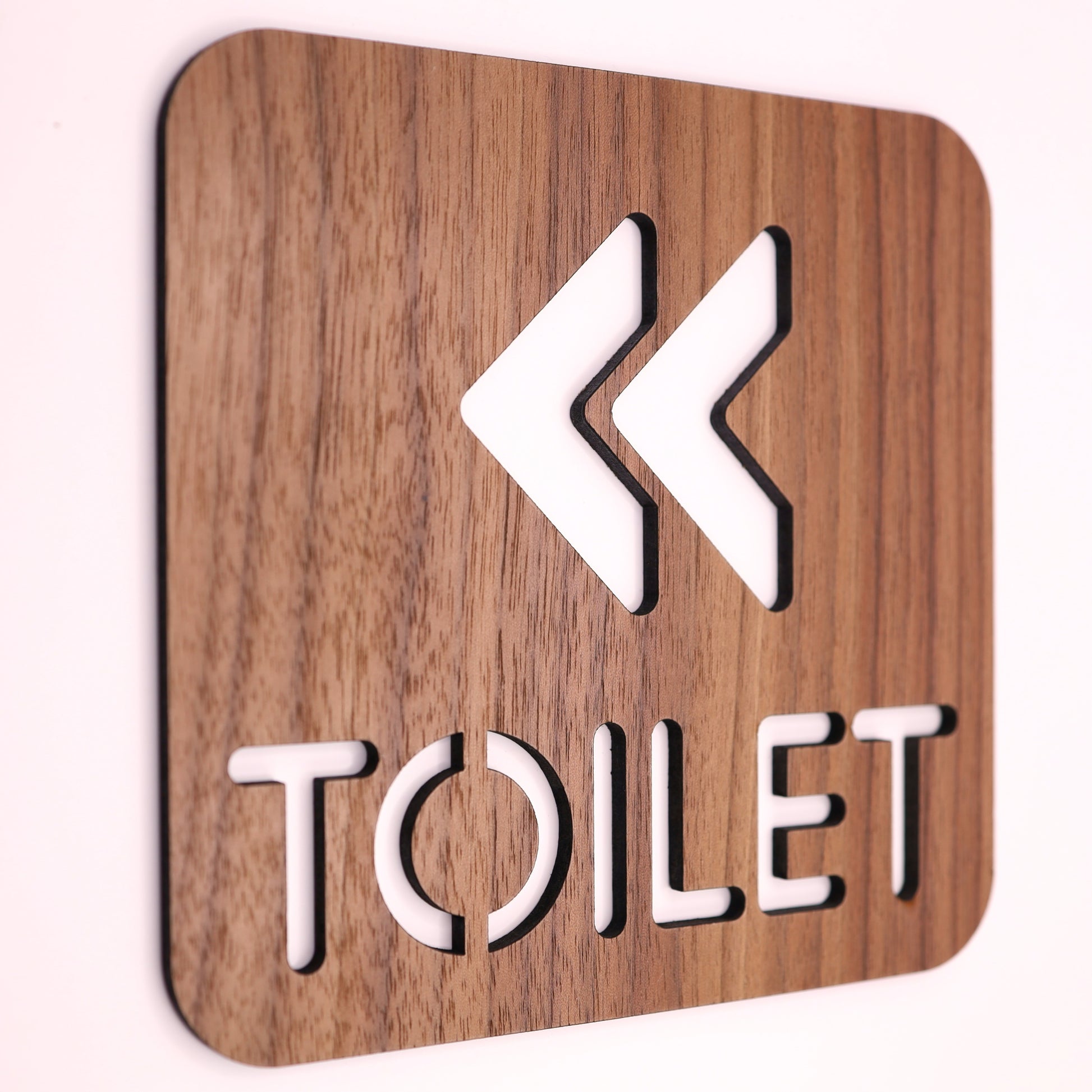 Modern engraved toilet sign on a wood surface, perfect for commercial spaces.